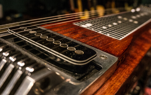Close up view of a wood guitar neck and guitar strings
