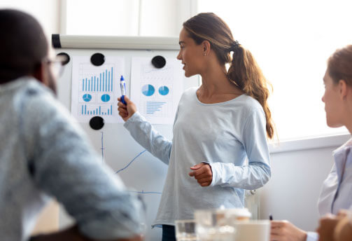 Female IT professional presenting data to two colleagues in a conference room 