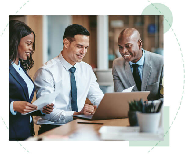 One female and two male business professionals sitting at a table while reviewing data on a laptop