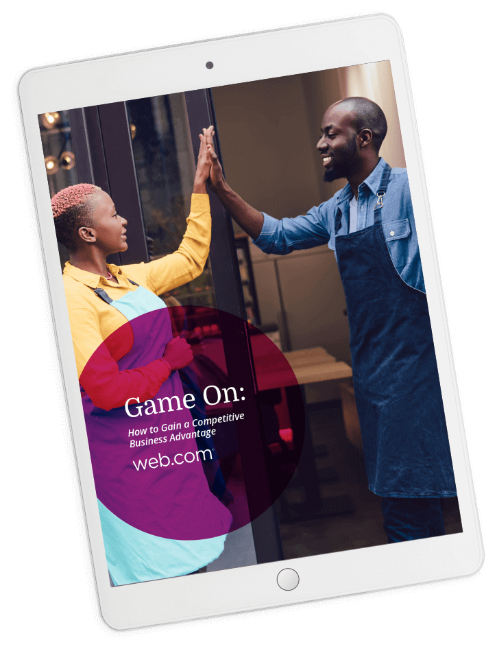 Tablet displaying the cover of the eBook ""How to Gain A Competitive Business Advantage"" featuring a man and woman wearing aprons giving high-fives outside of a their storefront