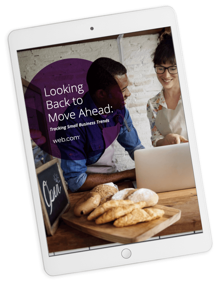 Tablet displaying the cover of the eBook "Tracking Small Business Trends" featuring a male and female baker looking at a laptop,  surrounded by bread in their bakery 