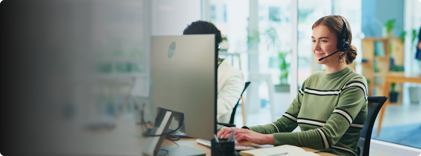 Smiling woman with headset in front of monitor