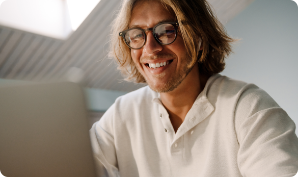 man smiling while looking at laptop