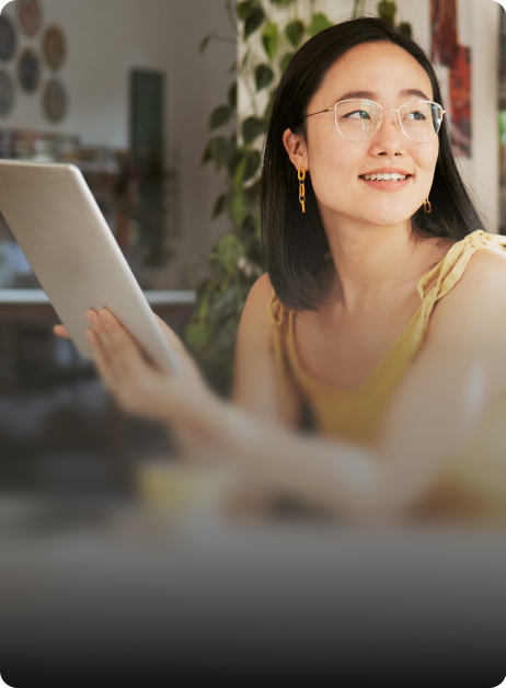 asian woman sitting on a cafe holding a tablet