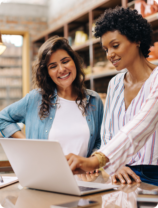 two women smiling at the laptop